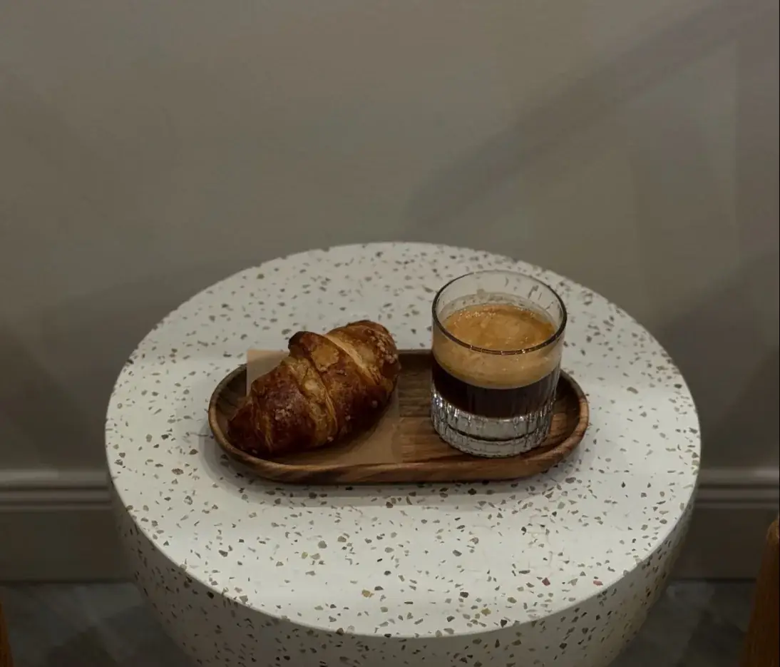 Espresso Tonic im Glas mit Croissant auf einem Terrazzo-Tisch